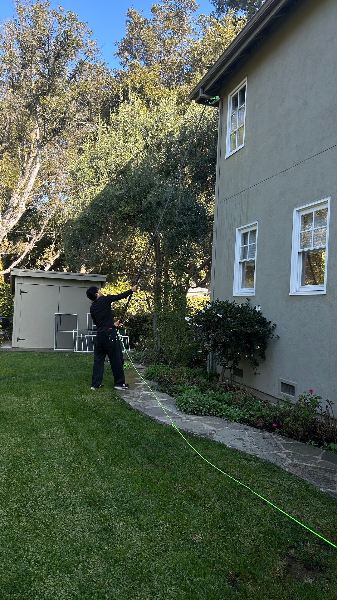 Water-fed pole reaching second-story windows on a stucco home
