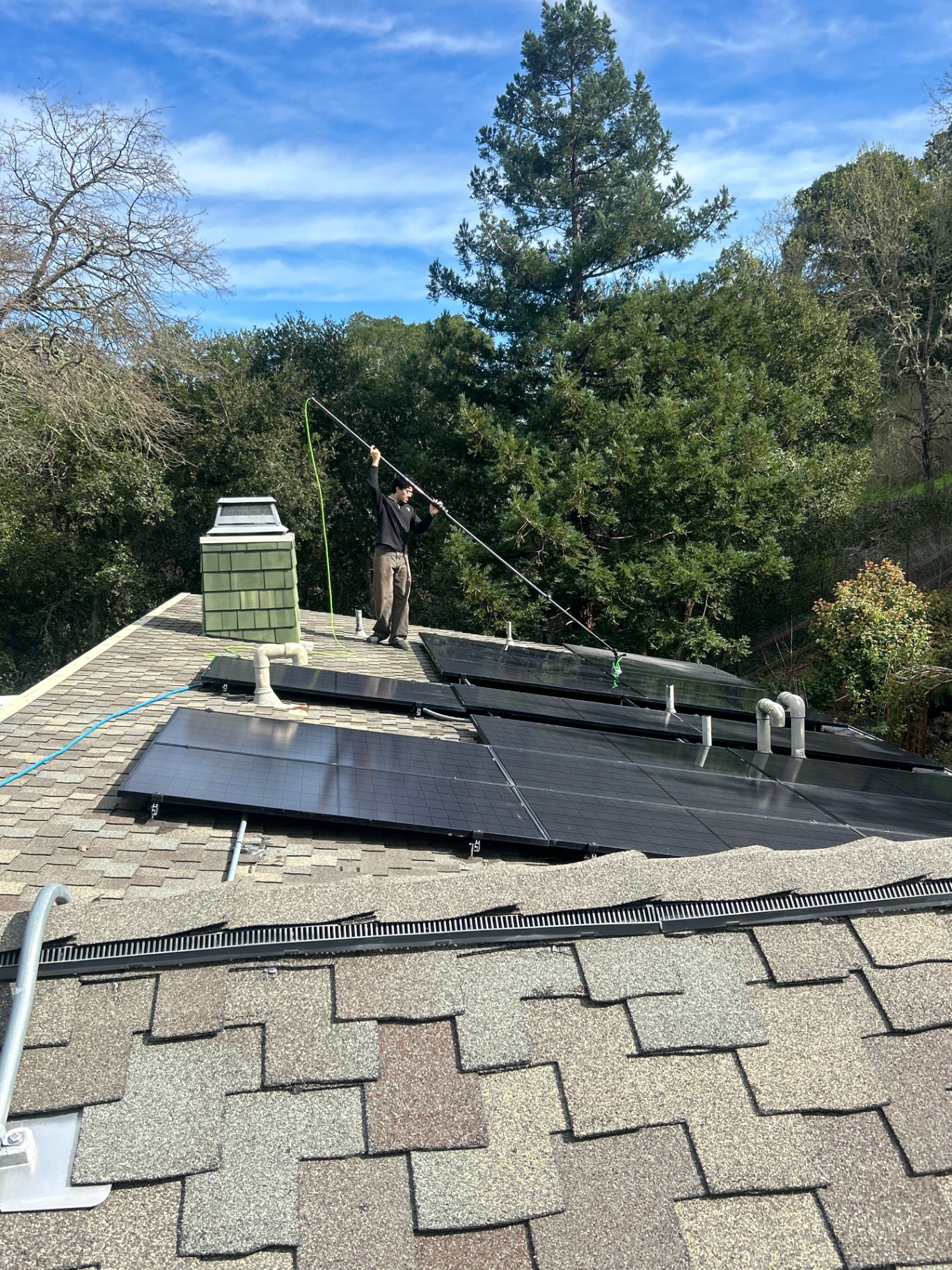 Technician cleaning rooftop solar panels on a Bay Area home