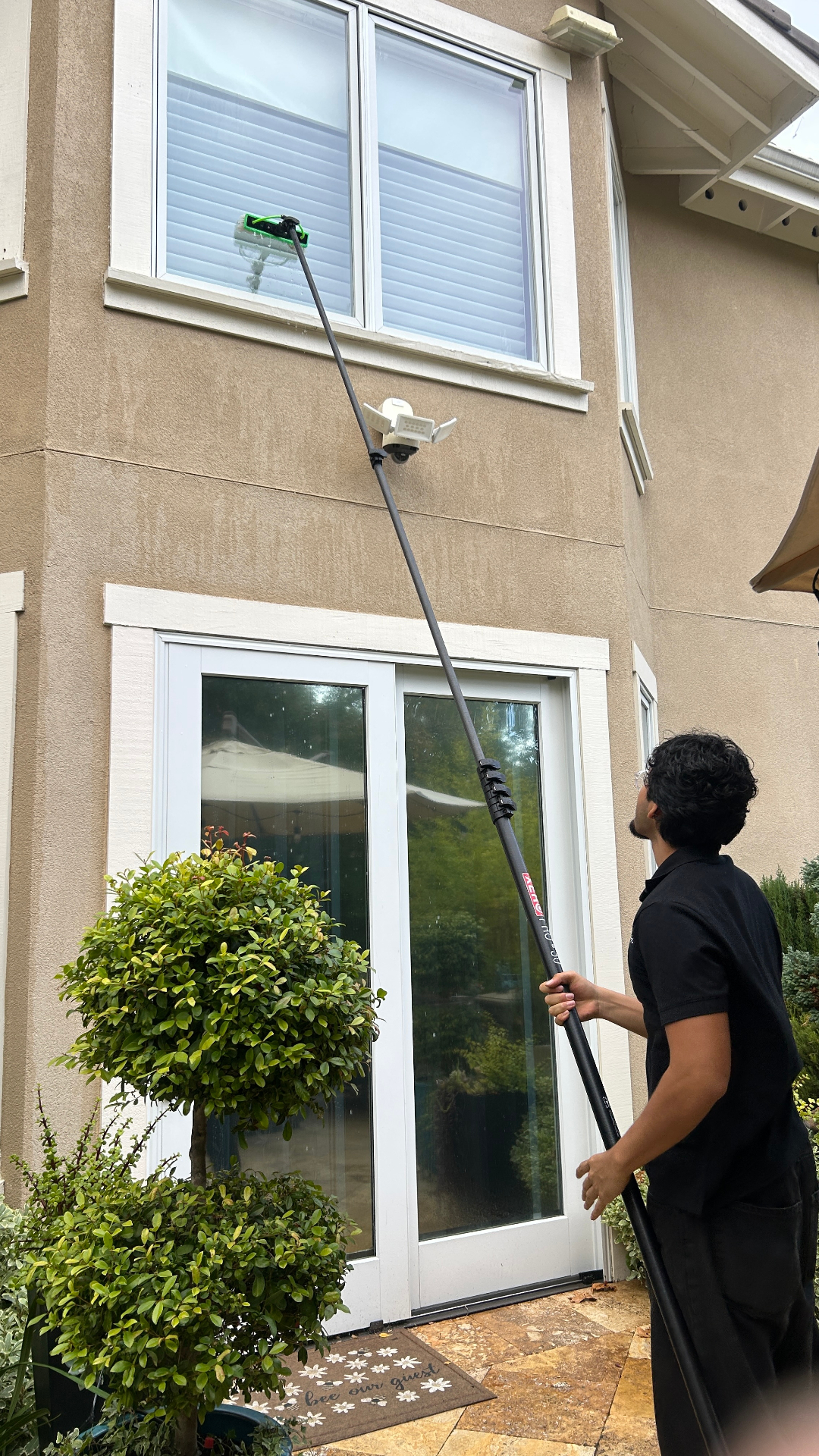 Technician cleaning second-story windows with a water-fed pole